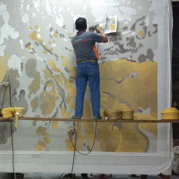 Artisan hand-tufting a custom abstract rug design on a frame in a studio